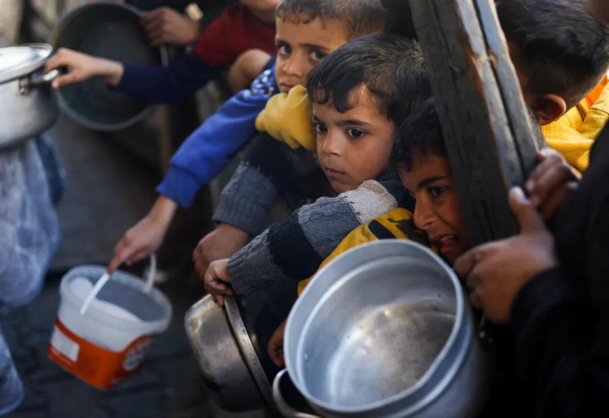 Palestinian children wait to receive food cooked by a charity kitchen amid shortages of food supplies in Rafah, in the southern Gaza Strip, on March 5, 2024. (Mohammed Salem/Reuters)