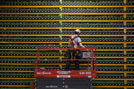 A technician inspects the backside of bitcoin mining at bitfarms in Saint Hyacinthe, Quebec, on March 19. (Lars Hagberg/AFP/Getty Images)