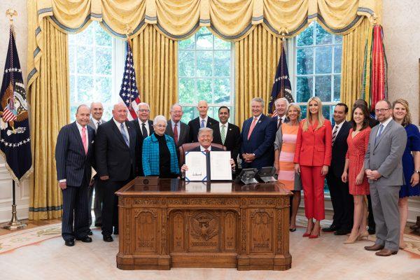 President Donald Trump, joined by members of Congress, senior White House staff and members of his cabinet, displays his signature on ‘H.R. 2353: Strengthening Career and Technical Education for the 21st Century Act’ in the Oval Office of the White House, on July 31, 2018. (Official White House Photo by Joyce N. Boghosian)