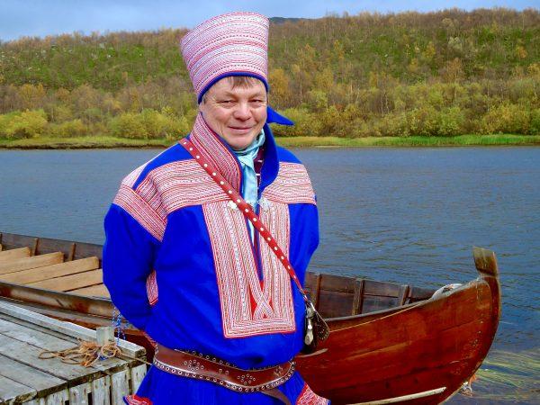 Johan Eira in traditional Sami regalia standing next to his boat. (Susan James)