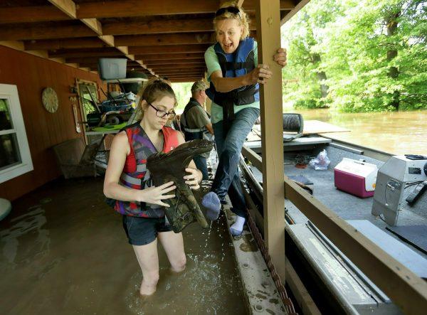 Emily Kientzel empties the water out of her grandmother Joan FitzGerald's boot that filled with floodwater from the Mississippi River, as they check on the home of a friend outside of Portage des Sioux, Mo., on June 2, 2019. (David Carson/St. Louis Post-Dispatch via AP)