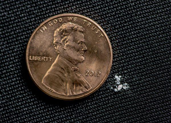 Photo illustration of 2 milligrams of fentanyl—a lethal dose for most people—next to a one cent coin. (DEA)