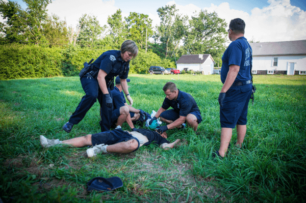 Local police and paramedics help a man who is overdosing in the Drexel neighborhood of Dayton, Ohio, on Aug. 3, 2017. (Benjamin Chasteen/The Epoch Times)