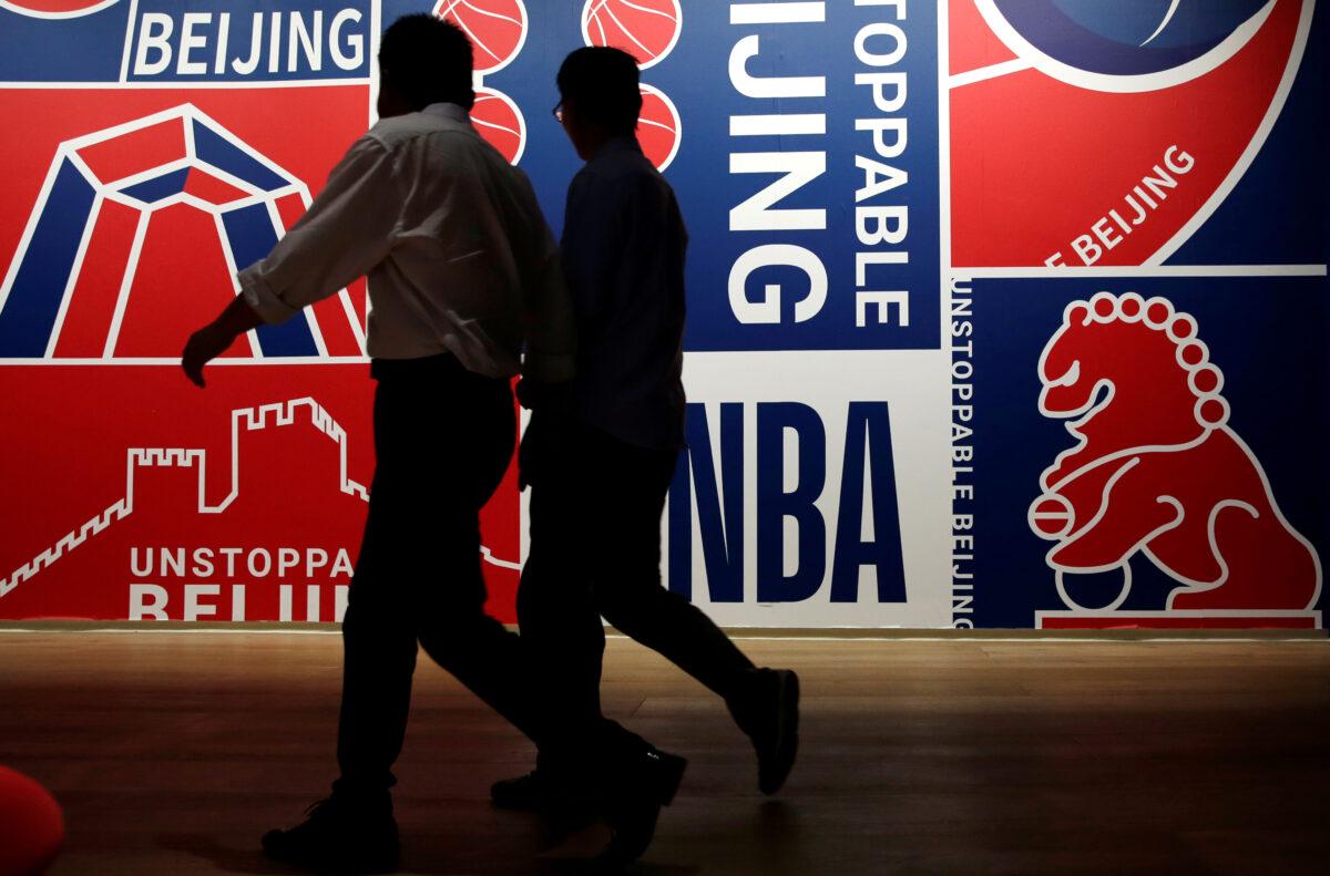 Men walk past a poster at an NBA exhibition in Beijing, on Oct. 8, 2019. (Jason Lee/Reuters)