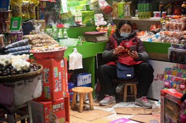 A vendor uses her cellphone as she waits for customers in Jiujiang, China, on March 6, 2020. (NOEL CELIS/AFP via Getty Images)