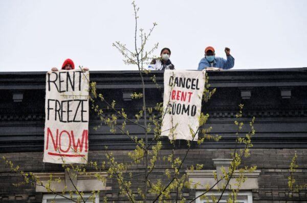 Building tenants hang signs from their roof in the Crown Heights neighborhood during a rent strike in New York City on May 1, 2020. (Angela Weiss/AFP via Getty Images)