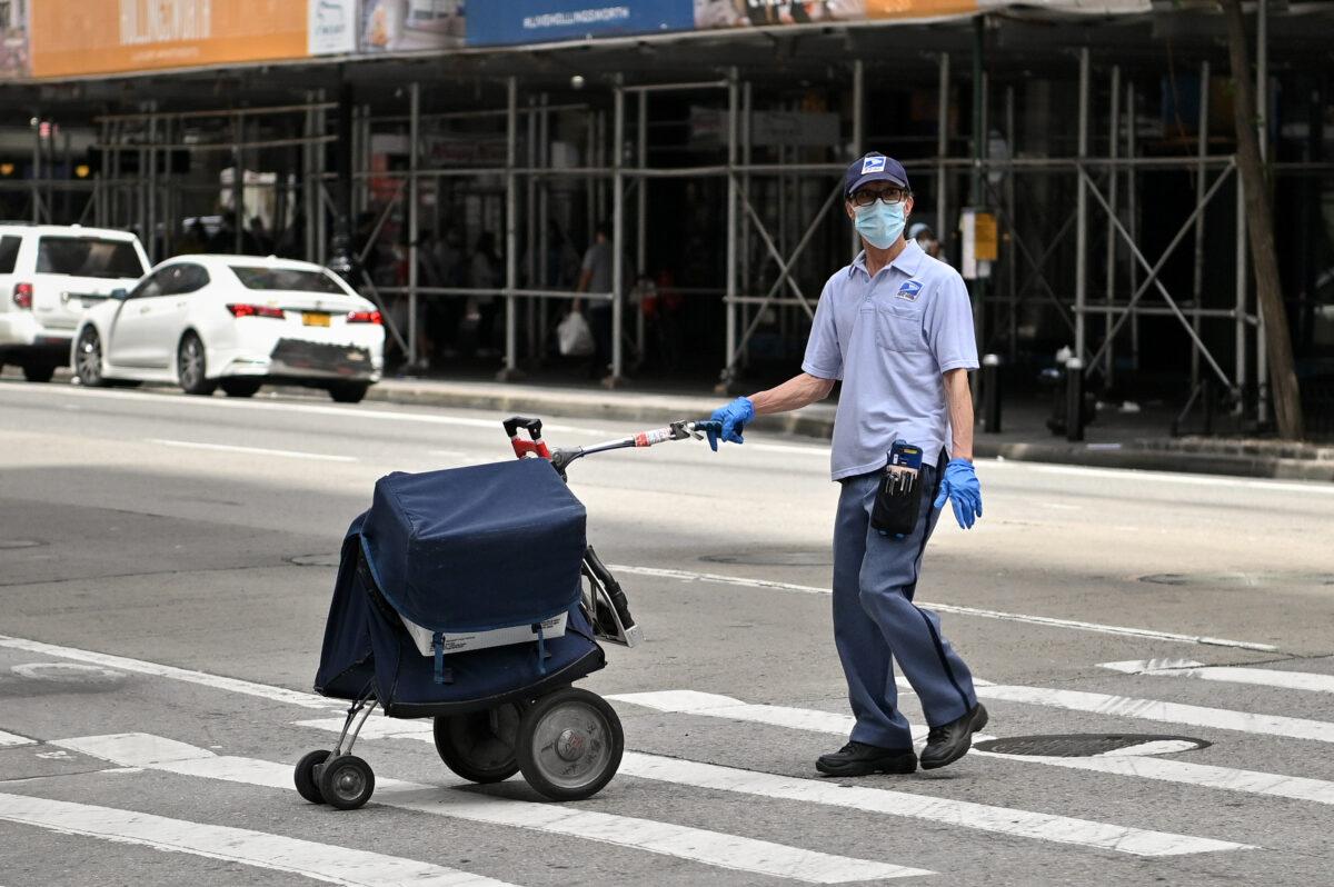 A U.S. Postal Service worker pushes a cart across the street in Midtown Manhattan during the COVID-19 pandemic, in New York City on May 22, 2020. (Dia Dipasupil/Getty Images)