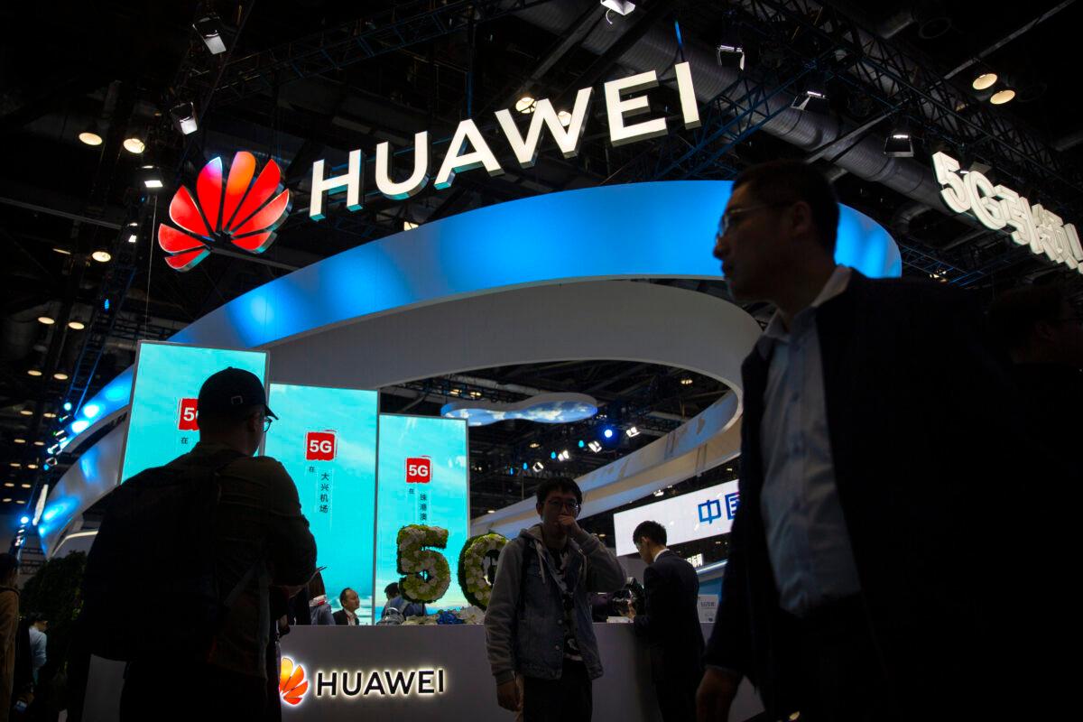 Attendees walk past a display for 5G services from Chinese technology firm Huawei at the PT Expo in Beijing, on Oct. 31, 2019. (Mark Schiefelbein/AP Photo)