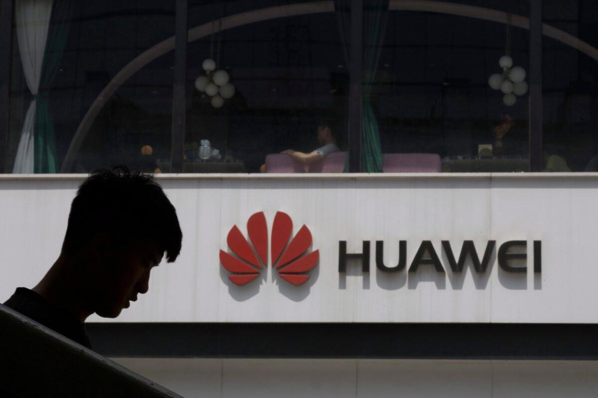 A Chinese man is silhouetted near the Huawei logo in Beijing on May 16, 2019. Conservative critics are calling for the federal government to ban the Chinese company from Canada's 5G network due to security concerns. (AP Photo/Ng Han Guan)