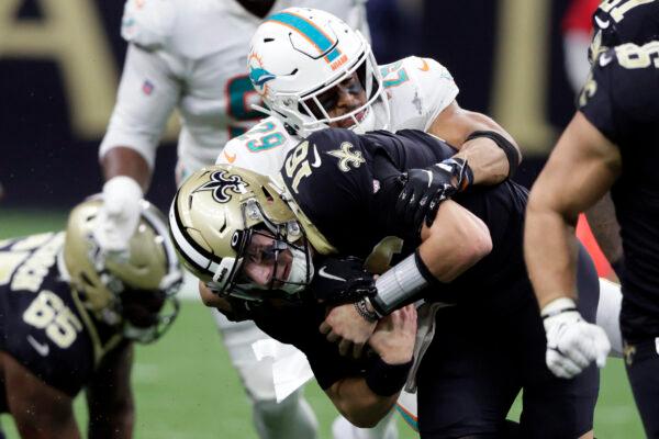 New Orleans Saints' Ian Book (16) is sacked by Miami Dolphins' Brandon Jones (29) during the second half of an NFL football game in New Orleans on Dec. 27, 2021. (Butch Dill/AP Photo)