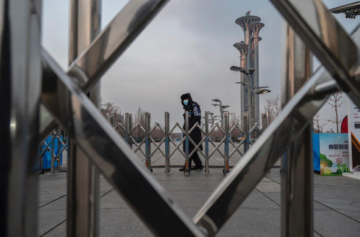 A security guard stands behind a barrier outside the National Stadium, also known as the Bird's Nest, that will be part of the closed-loop "bubble" for visitors and locals taking part in the Beijing 2022 Winter Olympics and Paralympics, in front of the Olympic Tower at the Olympic Park in Beijing, on Jan. 19, 2022. (Kevin Frayer/Getty Images)