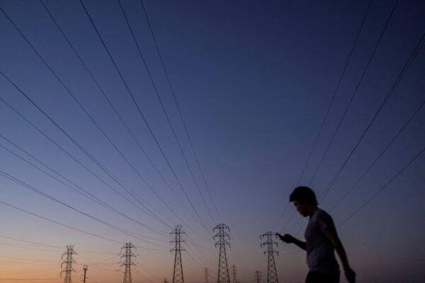 A man walks by power lines in Mountain View, Calif., on Aug. 17, 2022. (Carlos Barria/Reuters)