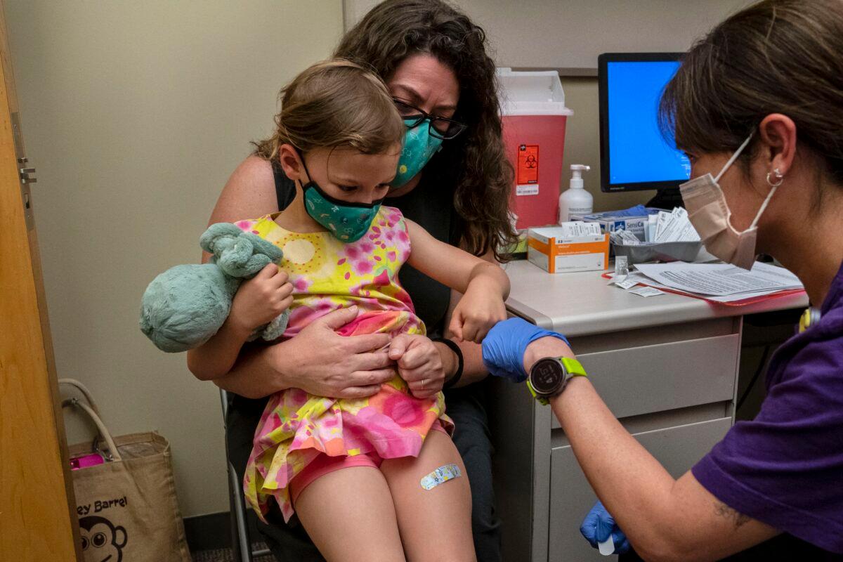 Nora Burlingame, 3, sits on the lap of her mother, Dina Burlingame, and gets a fist bump from nurse Luann Majeed after receiving her first dose of the Pfizer COVID-19 vaccination at UW Medical Center-Roosevelt in Seattle on June 21, 2022. (David Ryder/Getty Images)