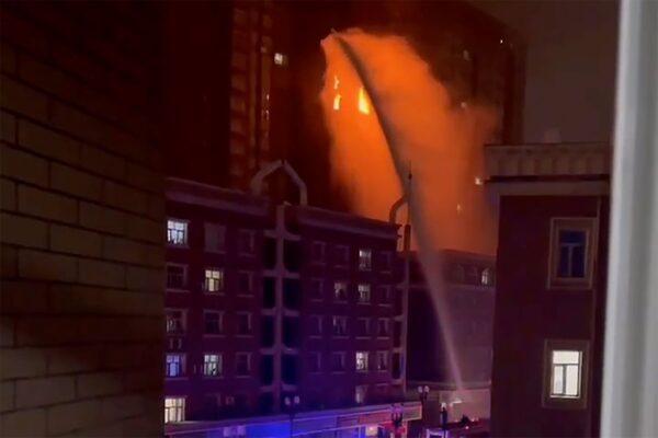 Firefighters spray water on a fire at a residential building in Urumqi, in western China's Xinjiang region, on Nov. 24, 2022, in a still from a video. From a different angle, it could be seen that the water could not reach the fire in the building due to firefighters reportedly being trapped outside a COVID-19 blockade. (AP Photo)