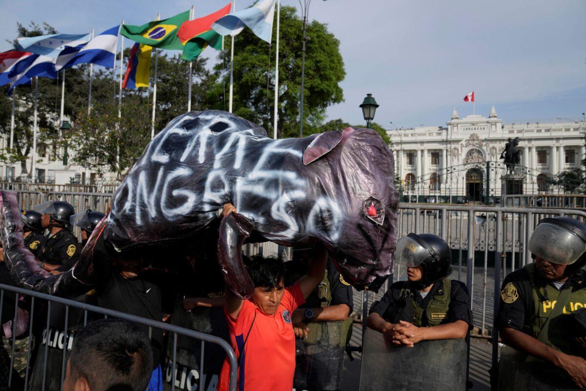 Supporters of ousted Peruvian President Pedro Castillo carry an inflated rat that reads in Spanish, "Close the Congress," as they pass in front of Congress in Lima, Peru, on Dec. 11, 2022. (Martin Mejia/AP Photo)