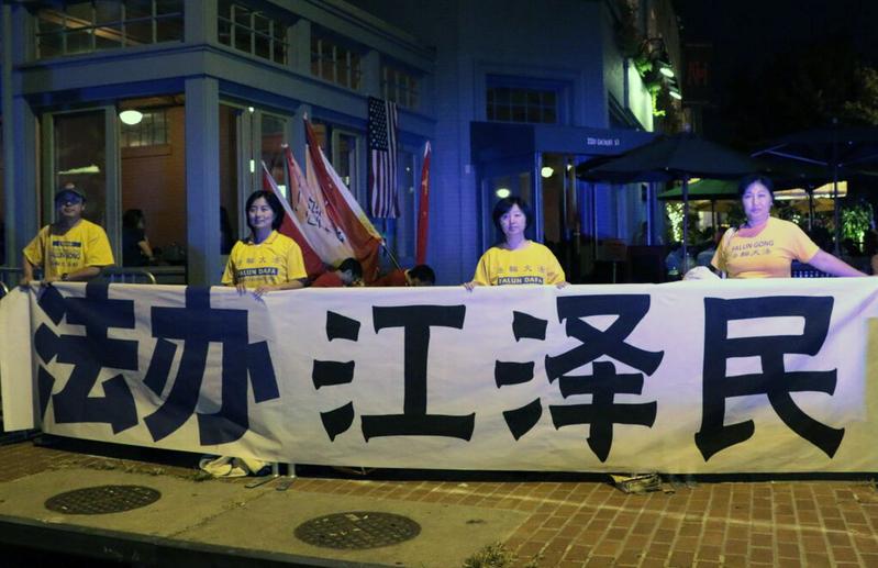 Falun Gong practitioners Zhang Huidong (L) and Yu Jing (R) hold a banner that reads "Bring Jiang Zemin to Justice," on Sept. 24, 2015. (Courtesy of Zhang Huidong)