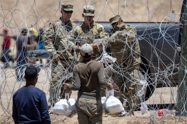 Texas National Guard soldiers close a section of razor wire surrounding a makeshift migrant camp as an immigrant tries to return with food for his family in El Paso, Texas, on May 11, 2023. (John Moore/Getty Images)