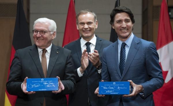 CEO of Volkswagen Group Oliver Blume (C) applauds as Prime Minister Justin Trudeau and German President Frank-Walter Steinmeier hold up EV battery cells they signed during an event on Parliament Hill in Ottawa on April 24, 2023. (The Canadian Press/Adrian Wyld)