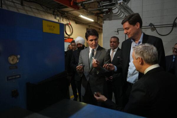 Prime Minister Justin Trudeau holds battery cells while talking with B.C Premier David Eby (2nd R) and Minister of Innovation, Science and Industry Francois-Philippe Champagne (R) during a tour of lithium battery manufacturer E-One Moli Energy (Canada), in Maple Ridge, B.C., on Nov. 14, 2023. (The Canadian Press/Darryl Dyck)