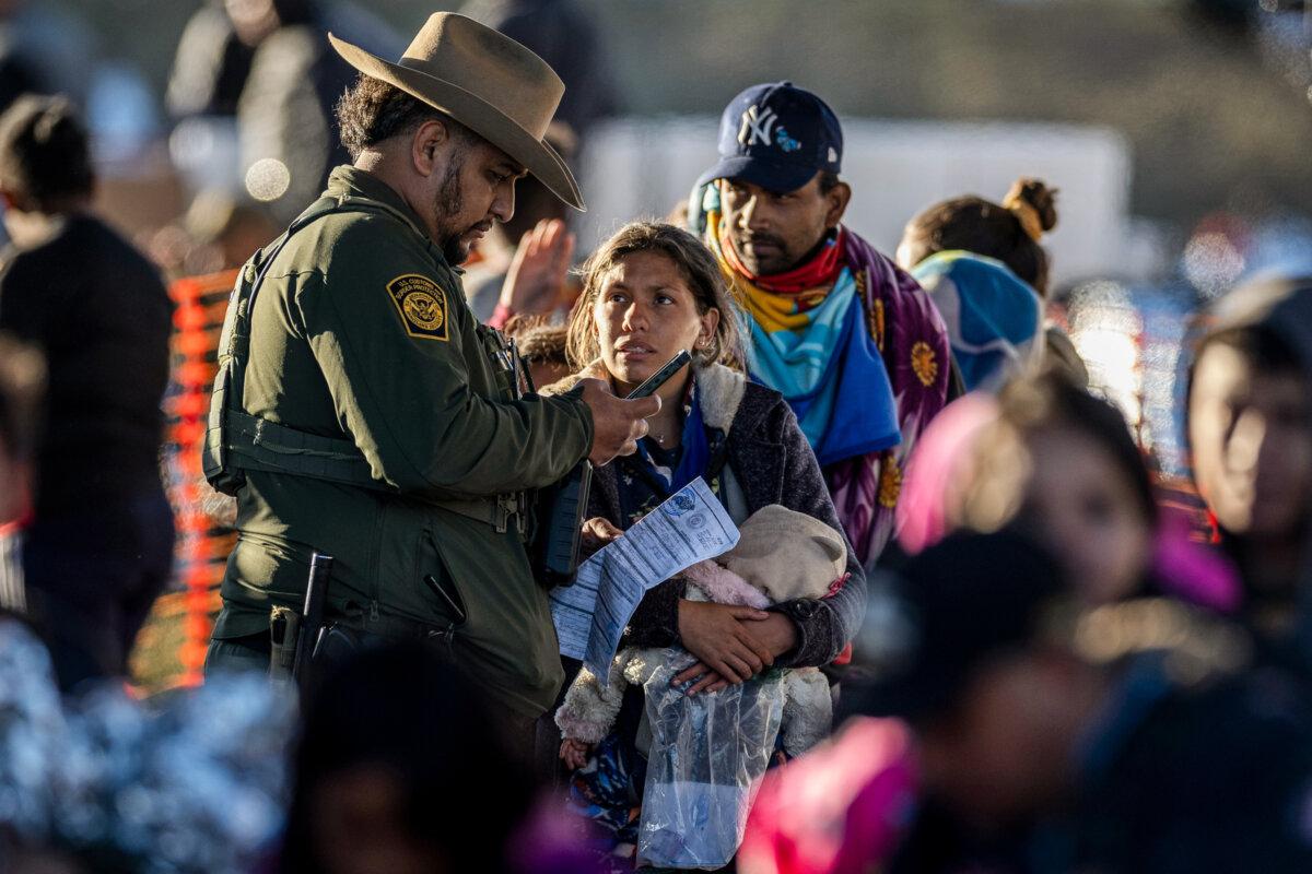 A U.S. Border Patrol agent speaks with illegal immigrants at a transit center near the U.S.–Mexico border in Eagle Pass, Texas, on Dec. 19, 2023. (John Moore/Getty Images)