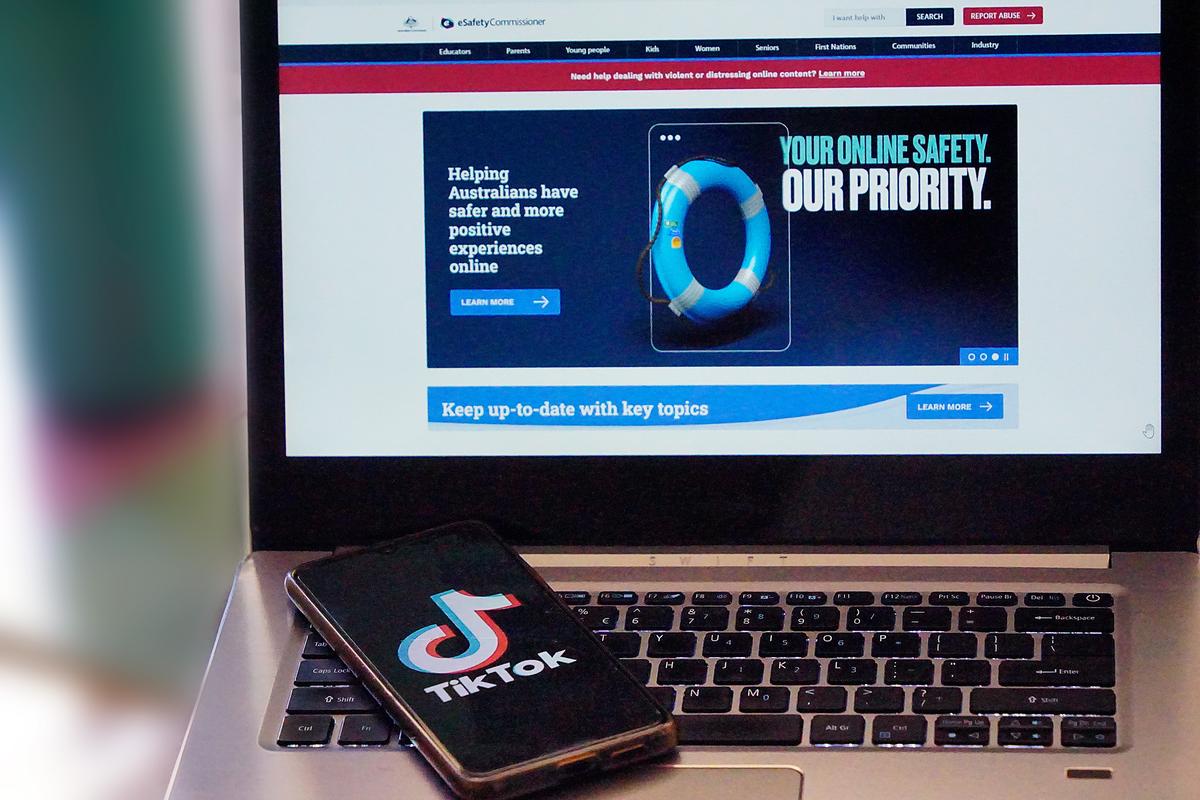 An image of the TikTok phone app in front of a laptop featuring the front page to Australia's eSafety commissioner website, taken in Perth, Western Australia on Jan. 20, 2024. (Wade Zhong/The Epoch Times)