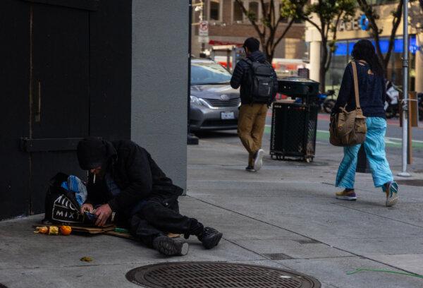 People walk by a drug addict in San Francisco on March 7, 2024. (John Fredricks/The Epoch Times)