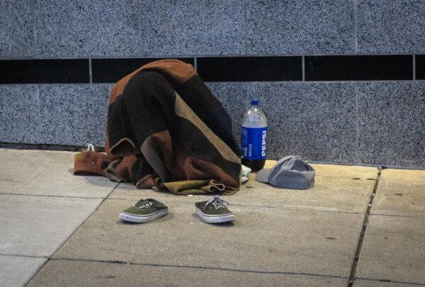 A homeless person covers up with a blanket in San Francisco on March 7, 2024. (John Fredricks/The Epoch Times)