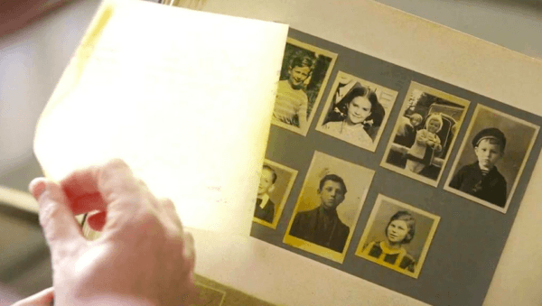 Nicholas Winton (Anthony Hopkins) looking through a scrapbook containing photos of the children he saved, in "One Life." (Warner Bros.)