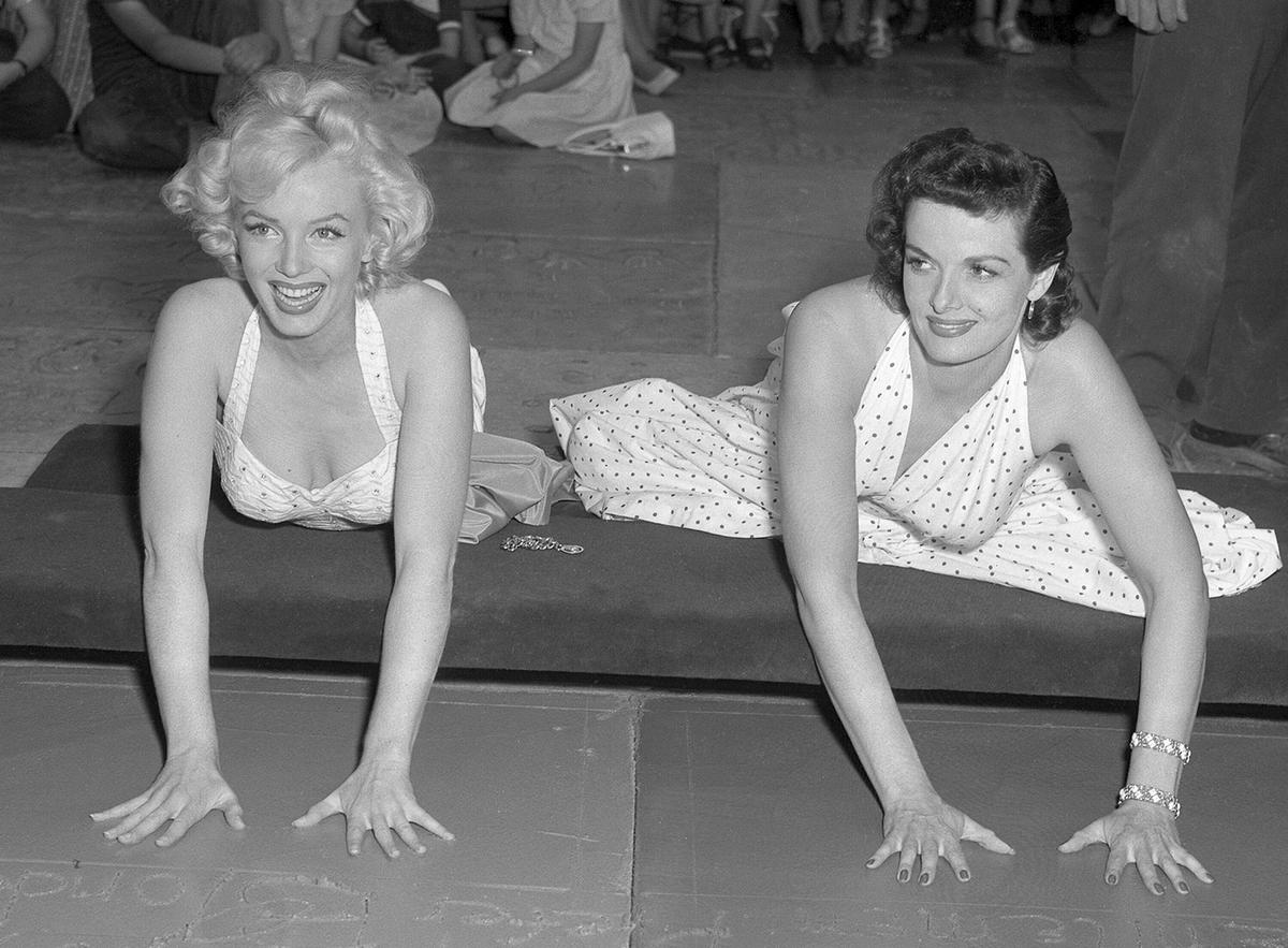 Leading stars of the 1953 film “Gentlemen Prefer Blondes,” Marilyn Monroe and Jane Russell are cementing their handprints at the Chinese Theater in Hollywood on June 27, 1953. <span style="font-weight: 400;">(</span><a href="https://digital.library.ucla.edu/catalog/ark:/21198/zz0002np7z"><span style="font-weight: 400;">Los Angeles Times Photographic Collection</span></a><span style="font-weight: 400;">/</span><a href="https://creativecommons.org/licenses/by/4.0"><span style="font-weight: 400;">CC-BY 4.0</span></a><span style="font-weight: 400;">)</span>