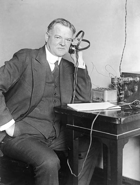 Secretary of Commerce Herbert Hoover listening to a radio receiver in 1925. The following year he conducted the first public long-distance television transmission. US Department of Commerce. (Public Domain)