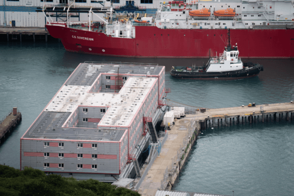 File photo of a tug boat passing the Bibby Stockholm accommodation barge at Portland Port in Dorset, which will house up to 500 people on March 20, 2024. (James Manning/PA Wire)