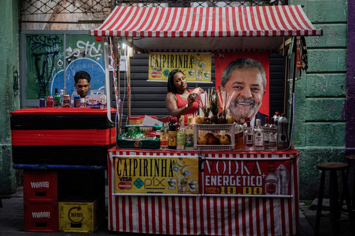 A supporter of Brazilian presidential hopeful Luiz Inácio Lula da Silva hangs a flag with a photo of the candidate on her street stall during the presidential runoff election, in Rio de Janeiro on Oct. 30, 2022. (Mauro Pimentel/AFP via Getty Images)