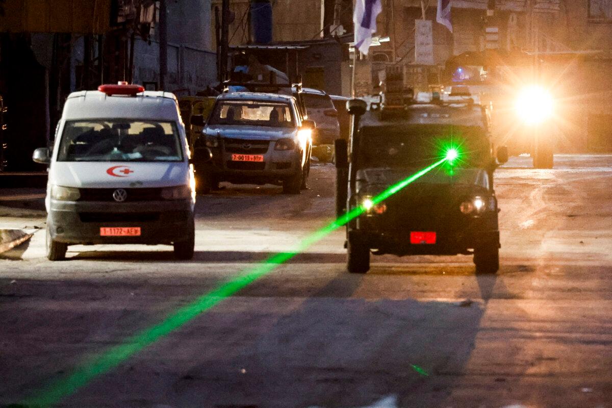 An Israeli military vehicle uses a laser on the day of an Israeli raid in Jenin, West Bank, on Jan. 21, 2025. (Raneen Sawafta/Reuters)