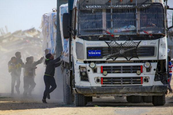 Palestinian children attempt to pull packets of humanitarian aid from a truck as it drives through Rafah in the southern Gaza Strip after crossing through the Kerem Shalom crossing on Feb. 18, 2025. (EYAD BABA/AFP via Getty Images)
