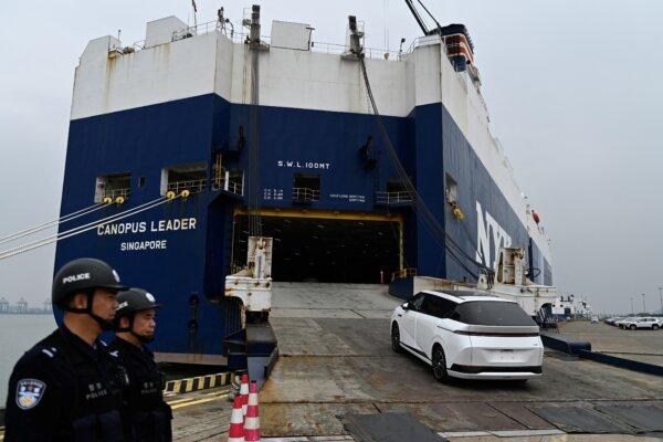 CCP Police officers watch a XPeng's X9 electric vehicle being loaded on a ship for Thailand in Guangzhou, China, on Feb. 22, 2025. (Pedro Pardo/AFP via Getty Images)
