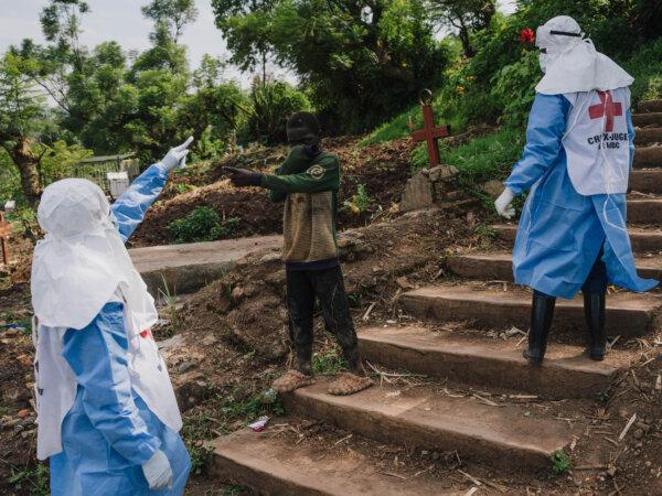 Teams of health workers from the Congolese Red Cross usher a child away during a mass burial at the Musigiko cemetery in Bukavu, Democratic Republic of Congo on Feb. 20, 2025. (Hugh Kinsella Cunningham/Getty Images)