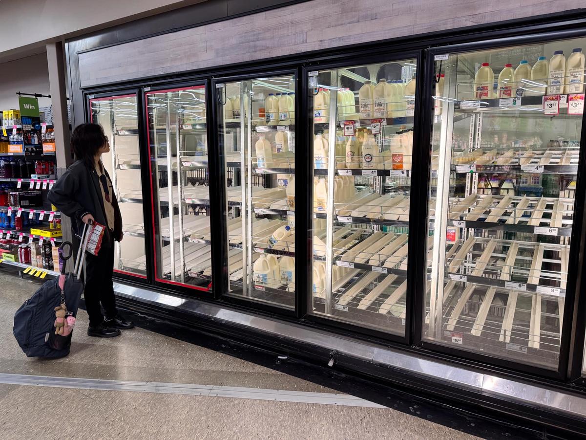 A customer standing before the milk section at a Woolworths store in Sunnybank Hills in Brisbane, Australia on March 3, 2025, as residents prepare for Cyclone Alfred. (Daniel Y. Teng/The Epoch Times)