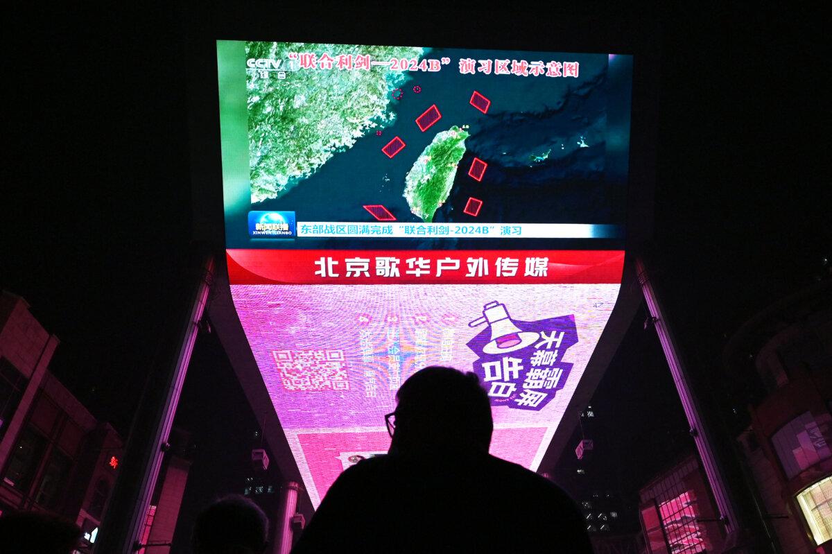 A man watches a news program about Chinese military drills surrounding Taiwan, on a giant screen outside a shopping mall in Beijing on Oct. 14, 2024. (Greg Baker/AFP via Getty Images)