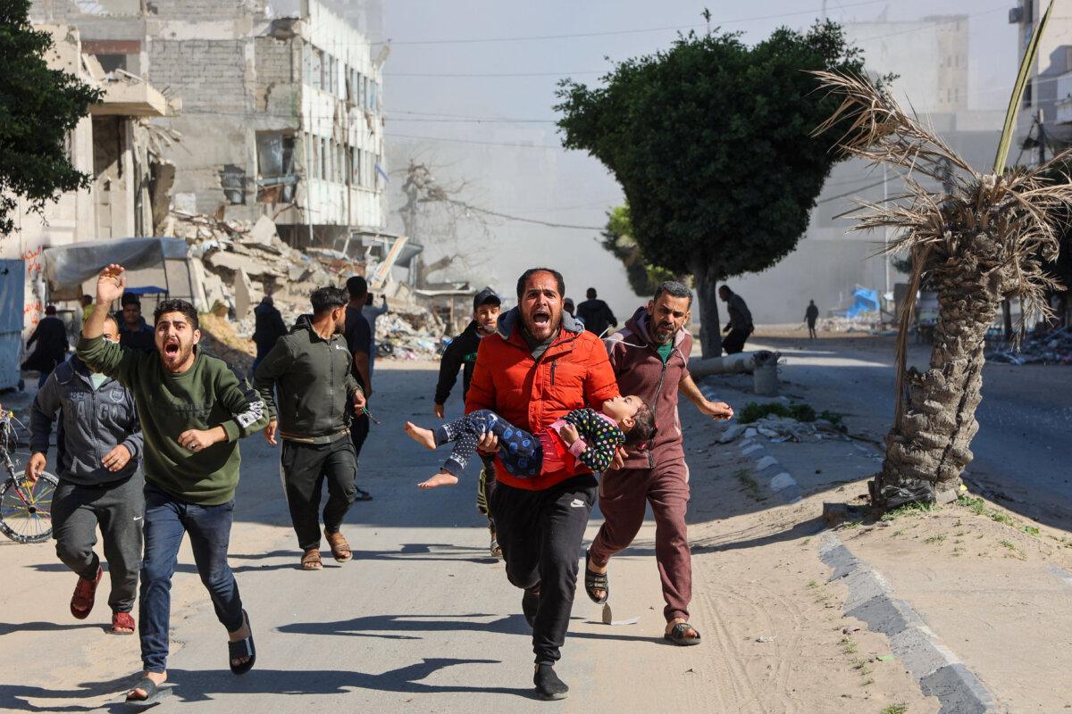 Palestinians rush an injured girl away from the site of Israeli strikes on a makeshift displacement camp in central Gaza City on March 23, 2025. (Omar Al-Qattaa/AFP via Getty Images)
