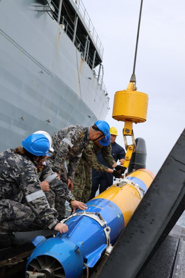 Crew from HMAS Collins and USS Emory S Land inspect the crane connection used to embark a Mk48 shape. (Courtesy of Australian Defence Force)