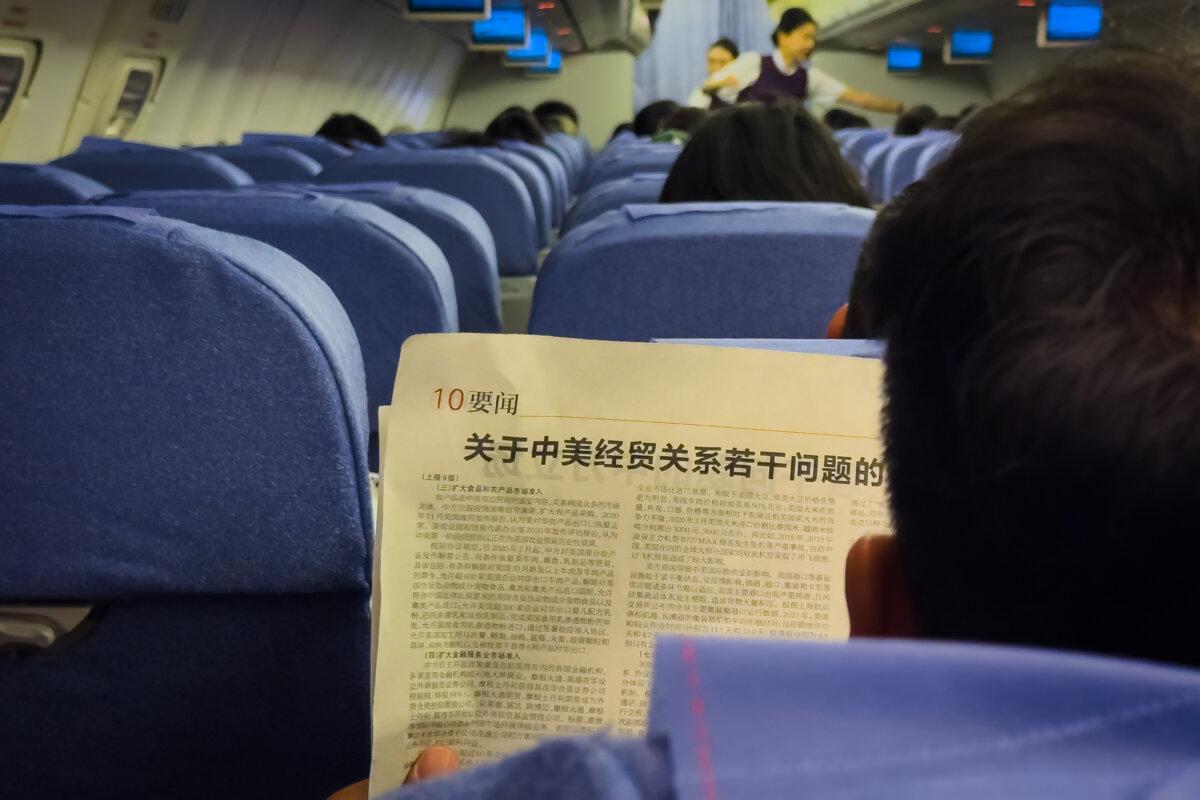 A passenger reads a newspaper article titled
