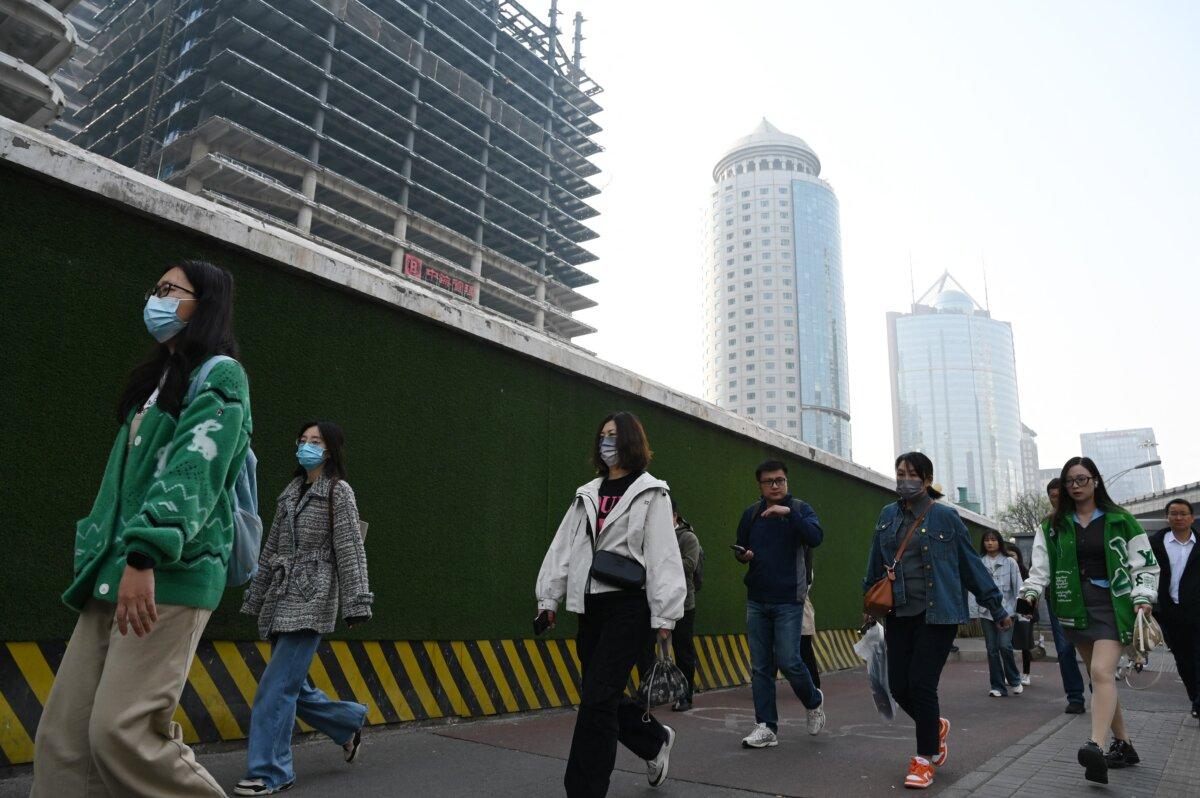 People walk past buildings in Beijing's central business district as they head to work on April 11, 2025. (Greg Baker/AFP via Getty Images)