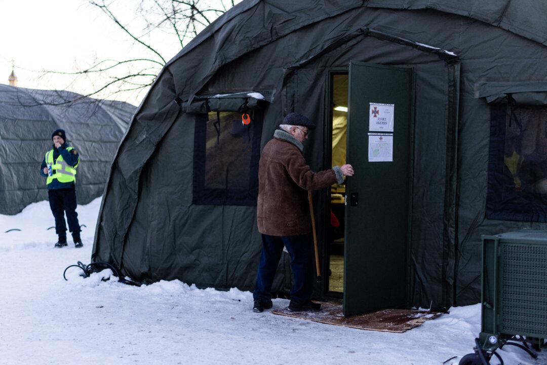 An elderly man opens the door of a humanitarian warming tent to enter in Kyiv, Ukraine on February 9, 2026. The scene shows residents seeking warmth, electricity, and hot food during ongoing power outages in winter conditions. (Photo by Daniel Yovkov / Hans Lucas / AFP via Getty Images)