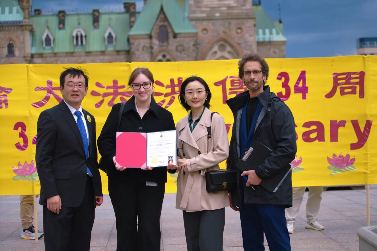 Falun Dafa Association of Canada representatives stand alongside an assistant of Liberal MP Amandeep Sodhi holding a proclamation from the MP marking World Falun Dafa Day, on Parliament Hill in Ottawa on May 5, 2026. (Evan Ning/The Epoch Times)
