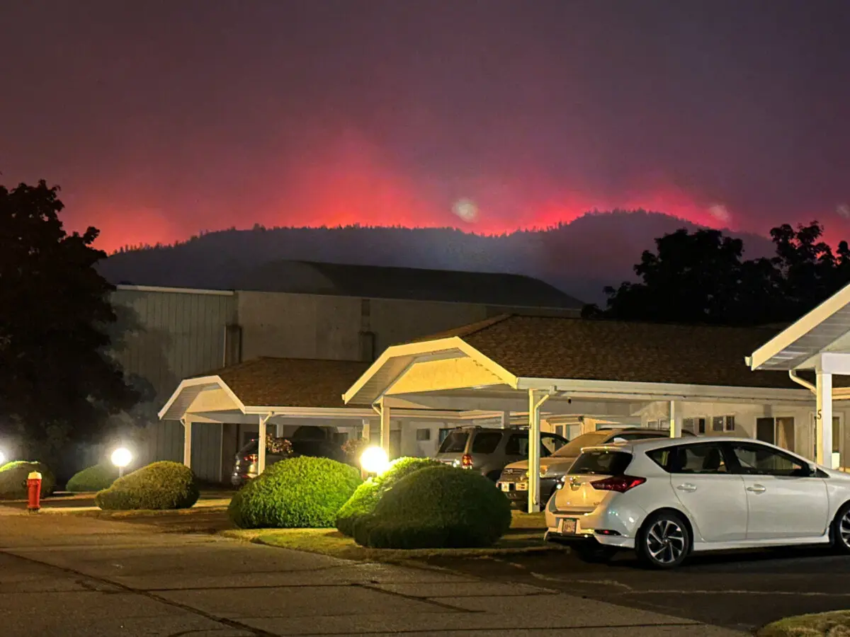 The Bald Range wildfire glows from behind hills near a residential street in Summerland, B.C., on Aug. 7, 2026. (Terry Fries/Handout via Reuters)