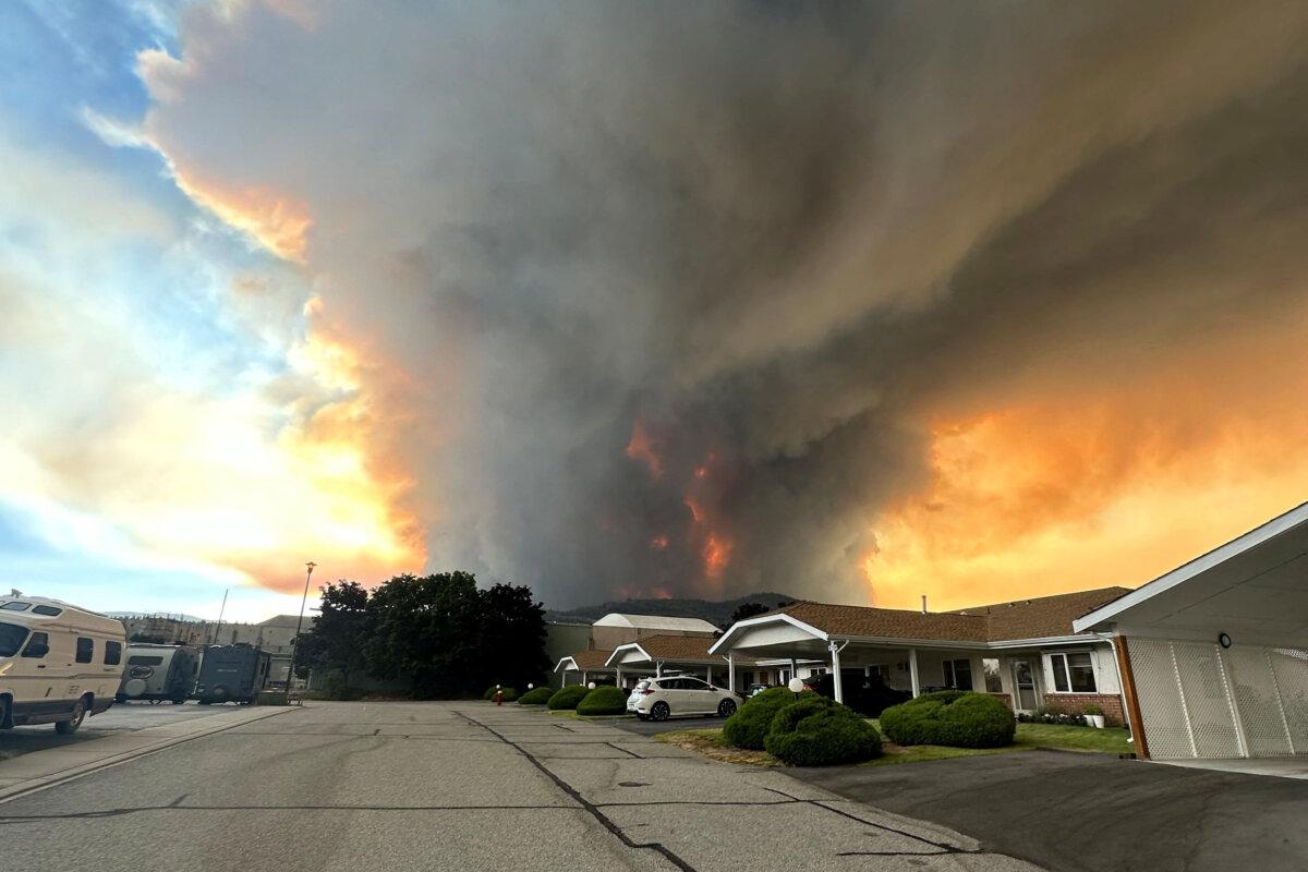 Smoke rises from the Bald Range wildfire over a residential street in Summerland, B.C., on Aug. 7, 2026. (Terry Fries/Handout via Reuters)