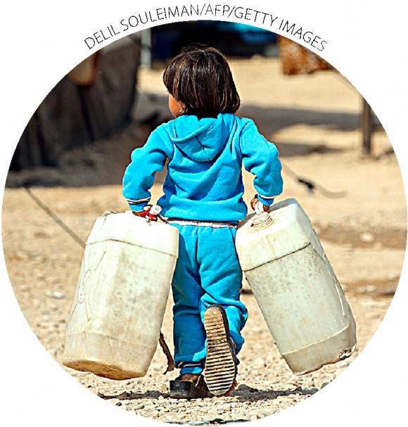 A girl carries water tanks in a refugee camp in Syria's Hasakah Province on Oct. 25.