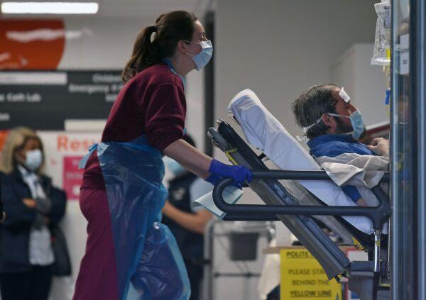 A medical professional in PPE pushes a patient inside St. Thomas's Hospital in north London, on April 1, 2020, (Daniel Leal-Olivas/AFP via Getty Images)