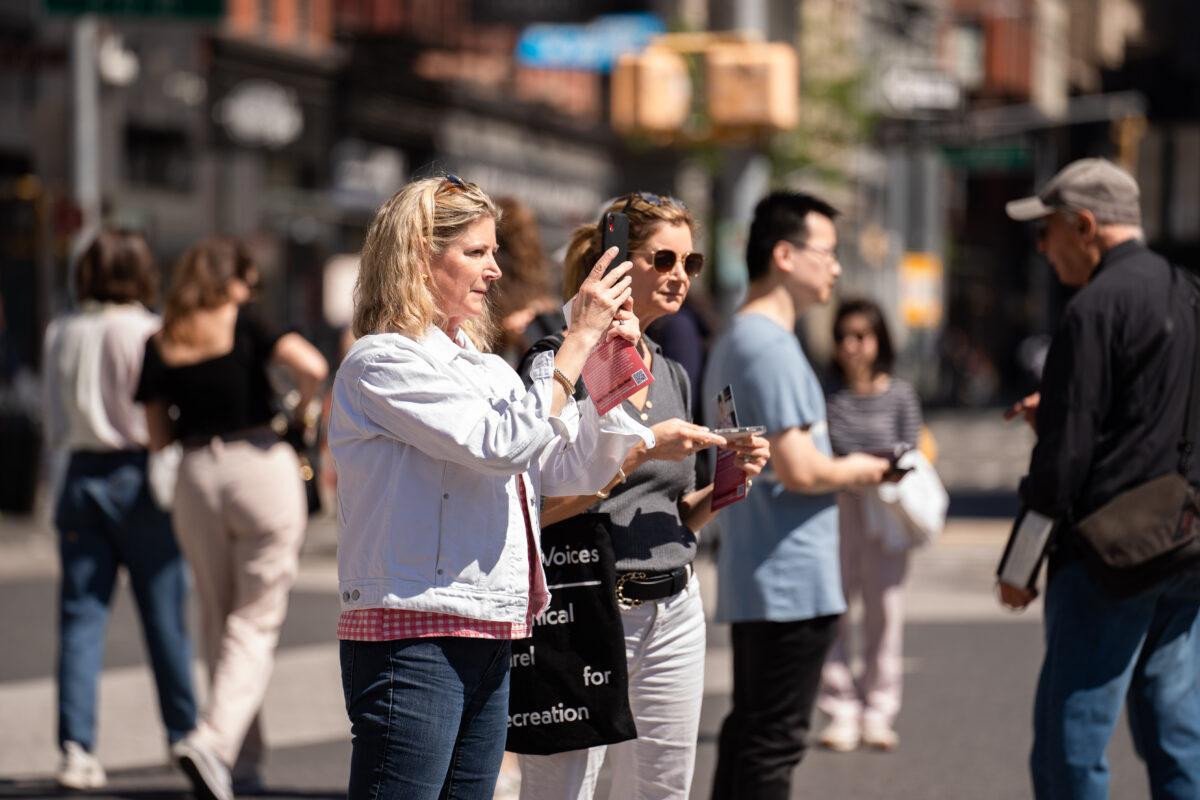 Passers-by take photos as Falun Gong practitioners celebrate World Falun Dafa Day in New York City on May 7, 2023. (Samira Bouaou/The Epoch Times)