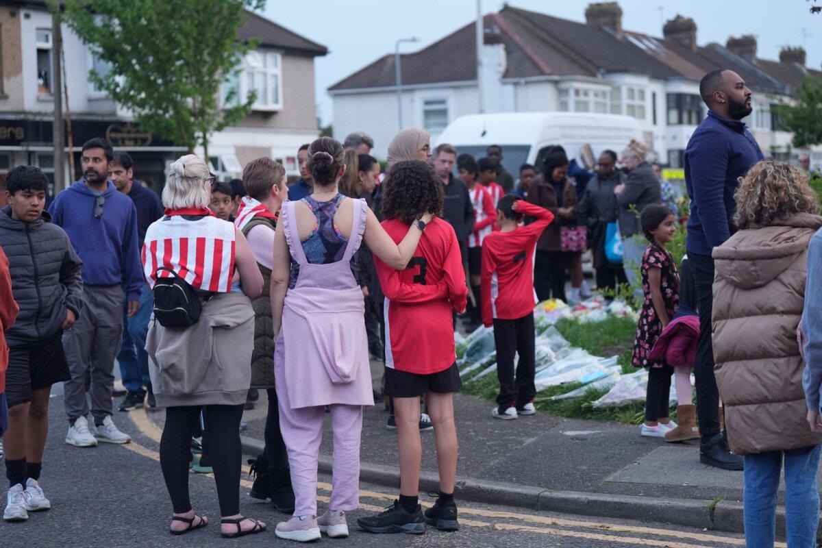 Members of the community, including players from River Hawks FC, look at floral tributes to Daniel Anjorin in Hainault, east London, on April 30, 2024. (PA)